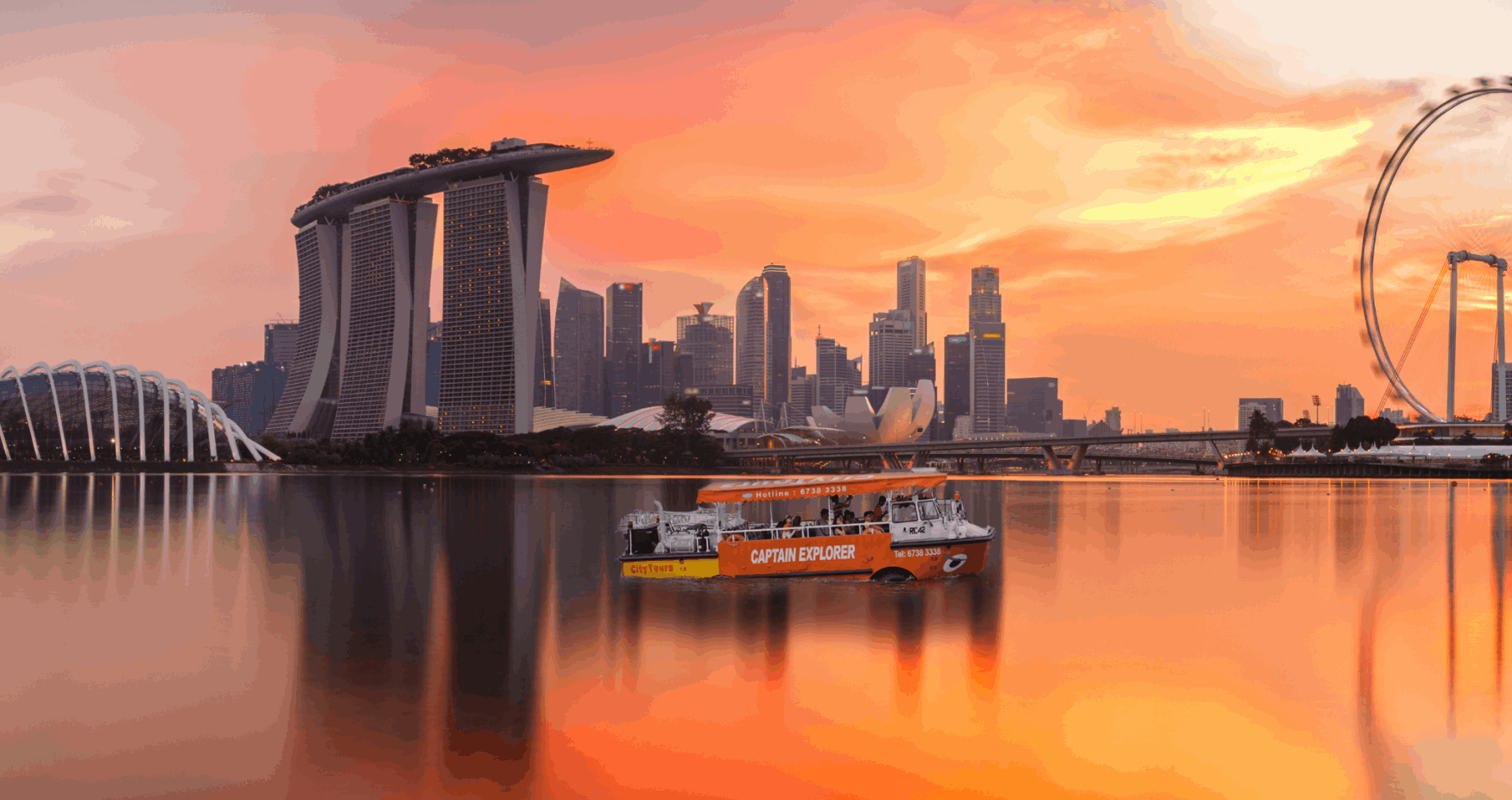 Captain Explorer DUKW Tour cruising through Marina Bay with Marina Bay Sands and Singapore’s city skyline in the background.