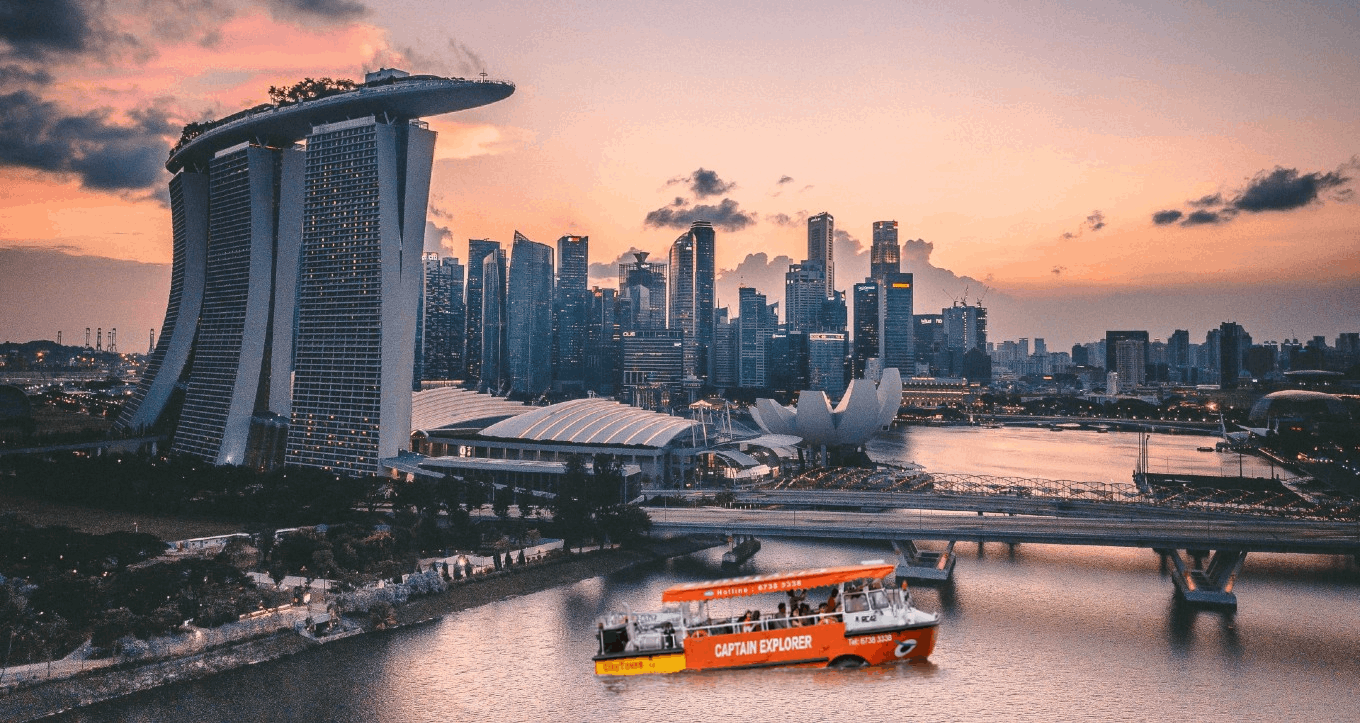 Captain Explorer DUKW Tour cruising along Marina Bay at sunset with Singapore skyline and Marina Bay Sands in the background.