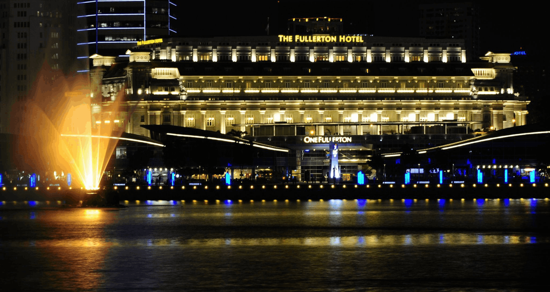 The Fullerton Hotel illuminated at night along the Singapore River, a scenic landmark to see while exploring Singapore after dark.
