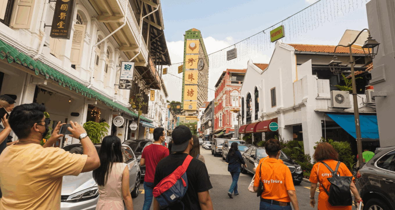 Visitors with City Tourist Guides exploring Chinatown street market decorated with hanging lanterns, surrounded by shops and vibrant cultural stalls.