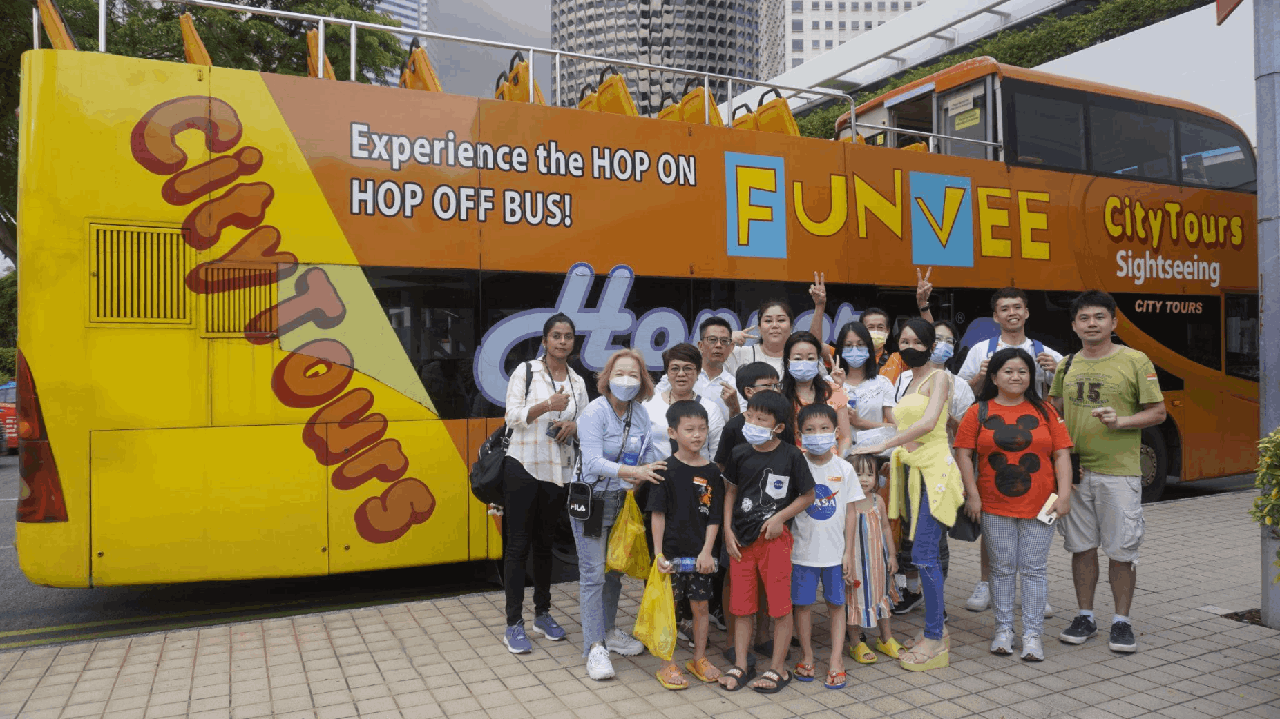 Families posing with the FunVee Hop-On Hop-Off Bus in Singapore, a family-friendly sightseeing option for first-time visitors exploring the city.