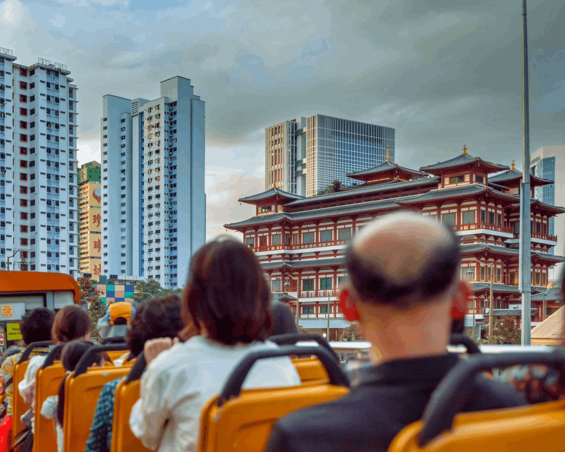Tourists on the upper deck of the FunVee Open-Top Bus photographing the Buddha Tooth Relic Temple in Chinatown