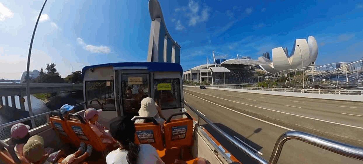 Passengers enjoying the FunVee open-top bus tour with views of Marina Bay Sands and ArtScience Museum in Singapore.