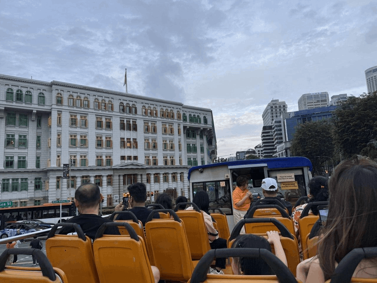 Tour guide speaking to passengers on the FunVee open-top bus driving through Singapore city streets