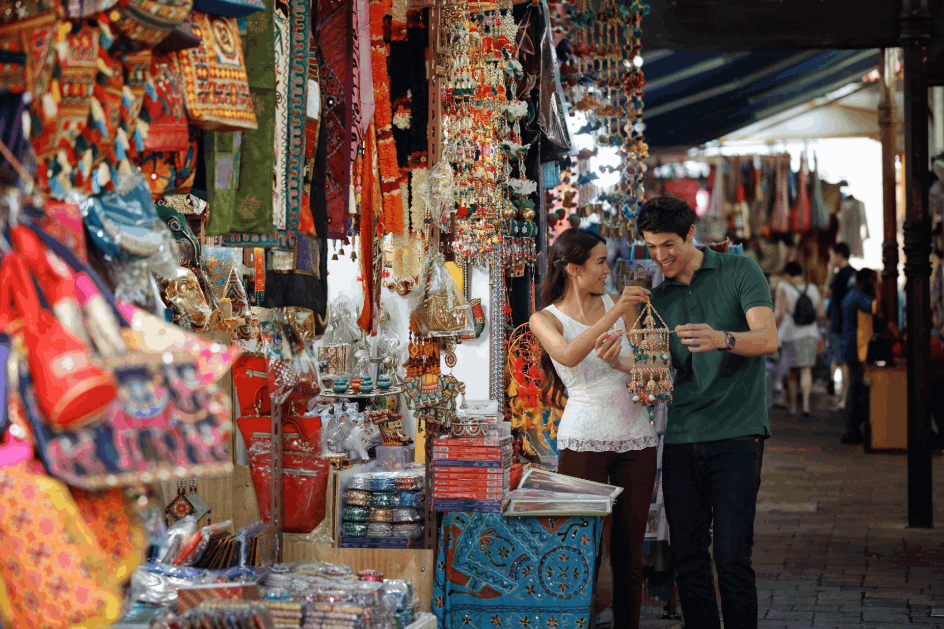 Couple browsing colourful souvenirs and textiles at Little India Arcade, a budget-friendly cultural shopping stop in Singapore.