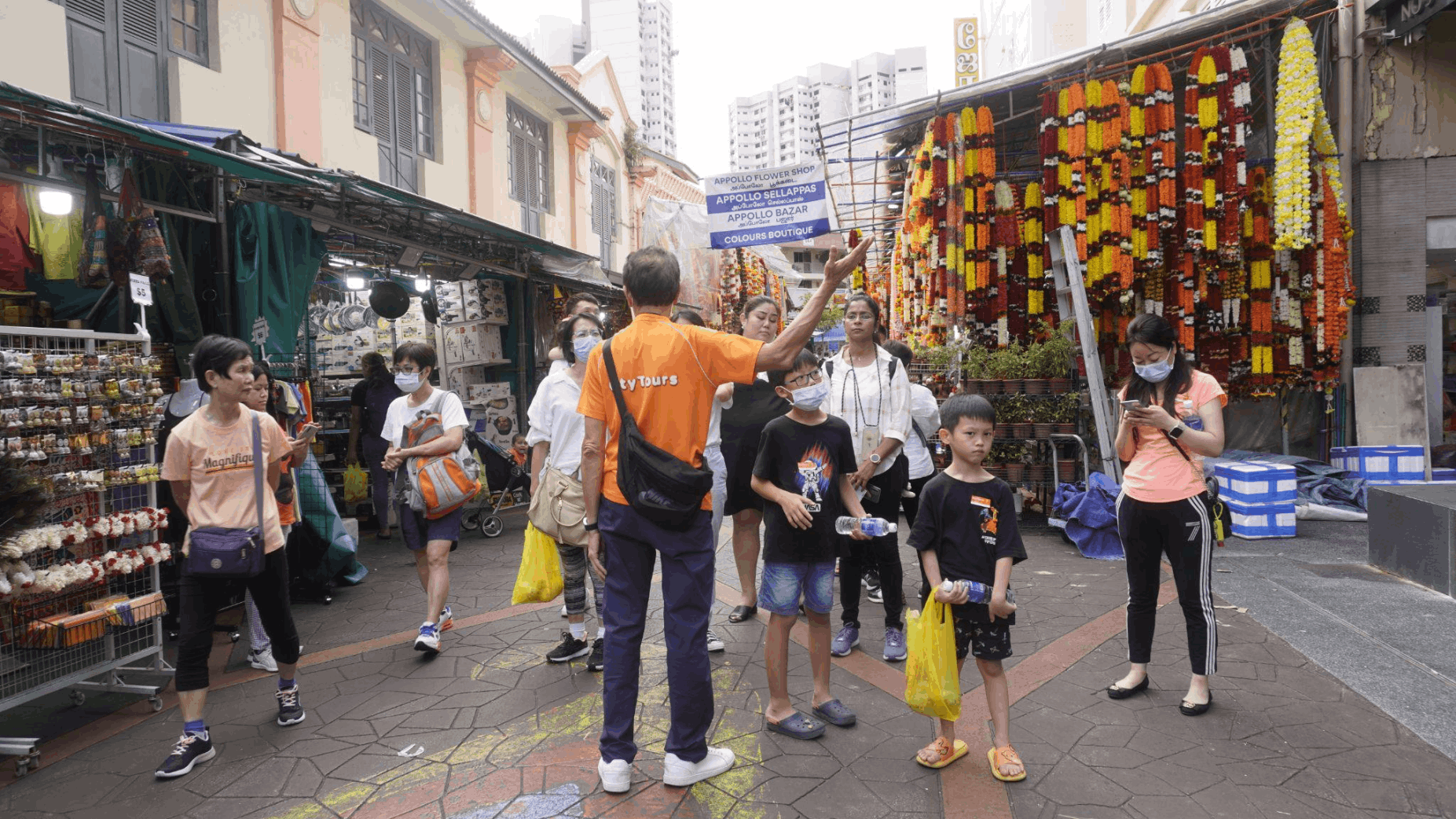 City Tours guide leading families through Little India’s colourful market stalls during an SG Culture Pass heritage walking tour in Singapore.
