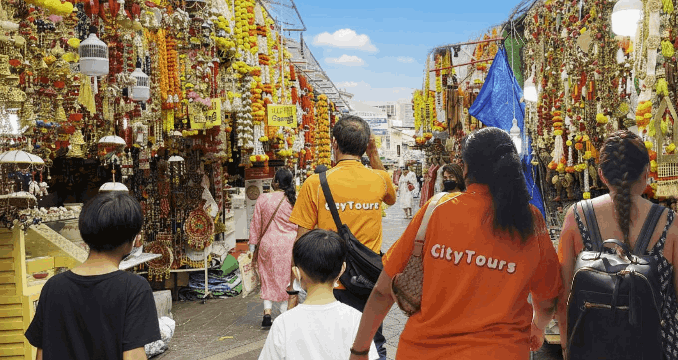 City Tours guide leading families through Little India’s colourful market stalls during an SG Culture Pass heritage walking tour in Singapore.