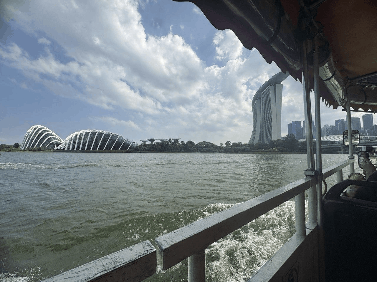 View of the Singapore skyline from the water during a Captain Explorer DUKW™ amphibious tour, featuring Marina Bay Sands, the Singapore Flyer, and Gardens by the Bay under a cloudy sky