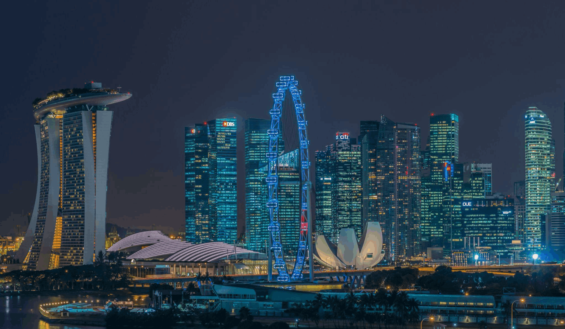 Singapore Flyer and Marina Bay skyline illuminated at night, a scenic evening view for visitors exploring Singapore after dark.