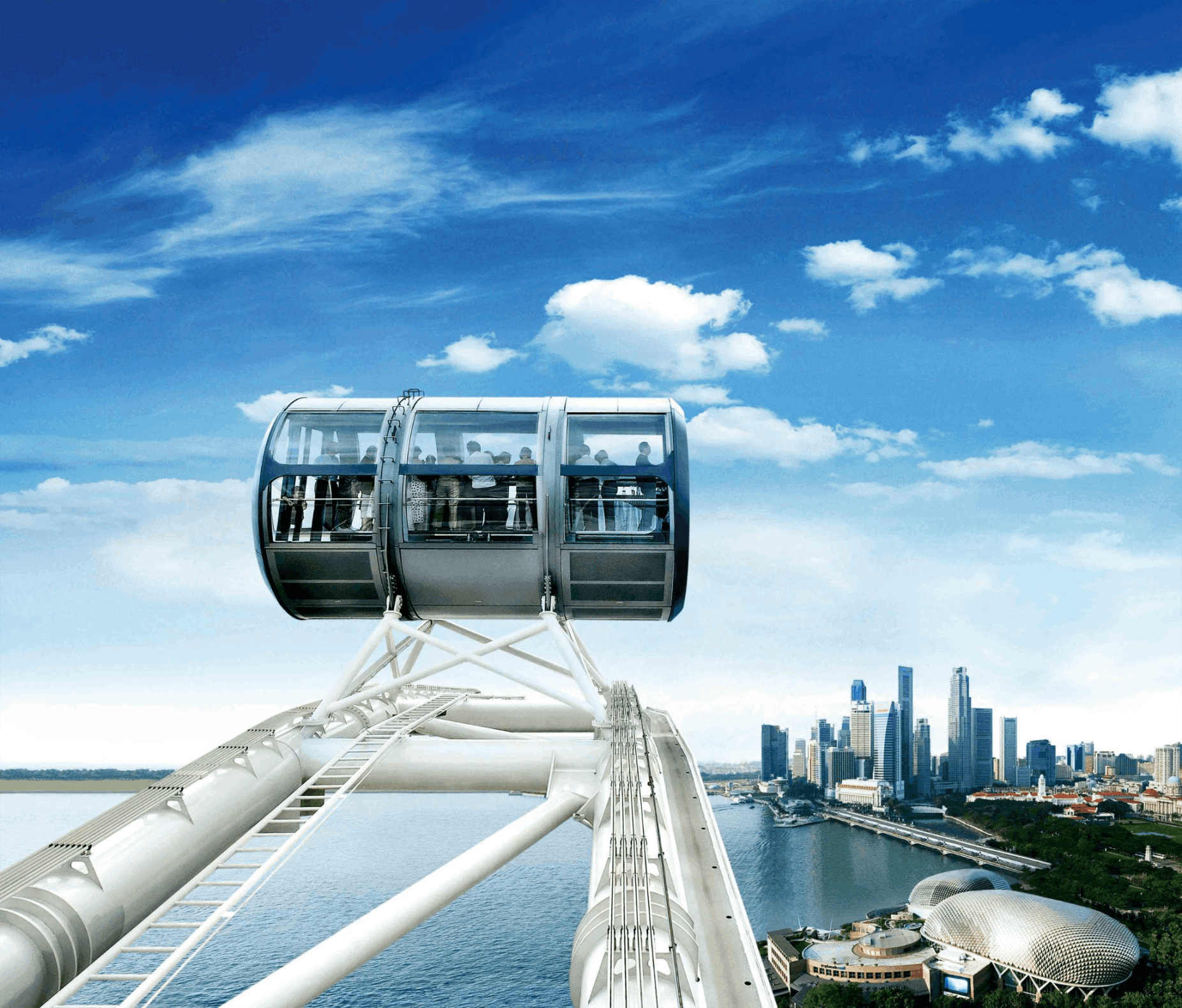 A high-altitude view of a Singapore Flyer observation capsule overlooking the Marina Bay district, Esplanade, and the central business district skyline under a bright blue summer sky