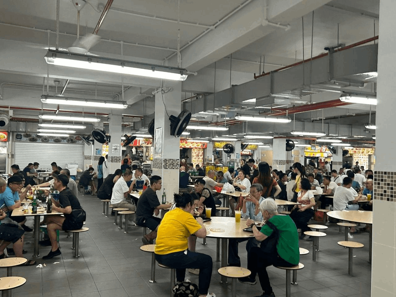 Busy Singapore hawker centre with locals and tourists enjoying affordable local food, a budget-friendly dining option for visitors.